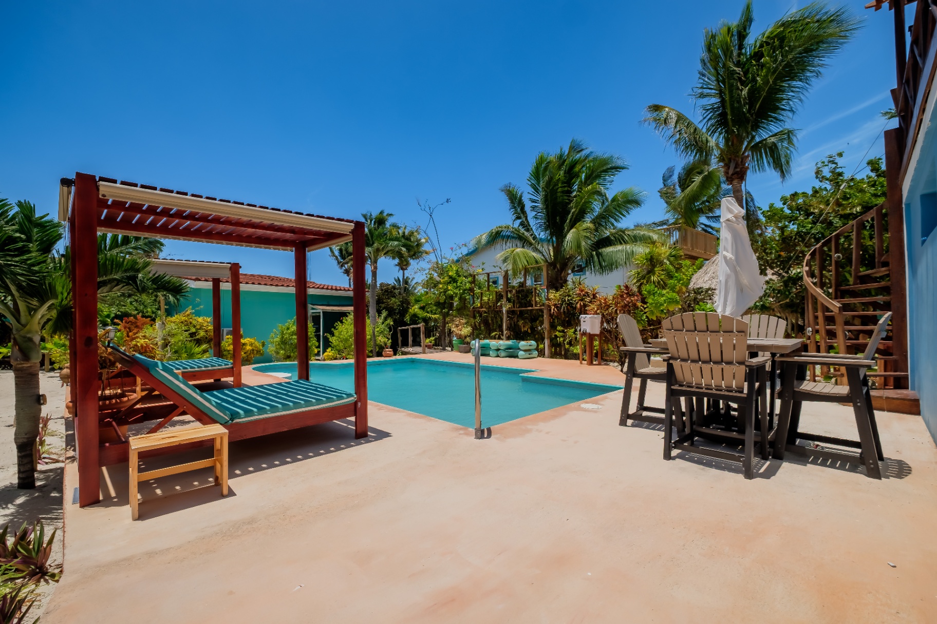 Pool deck with cabana daybed and Adirondack dining set