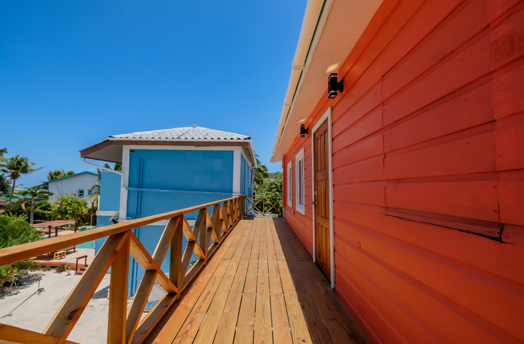 Elevated wooden boardwalk between the orange and blue cabanas
