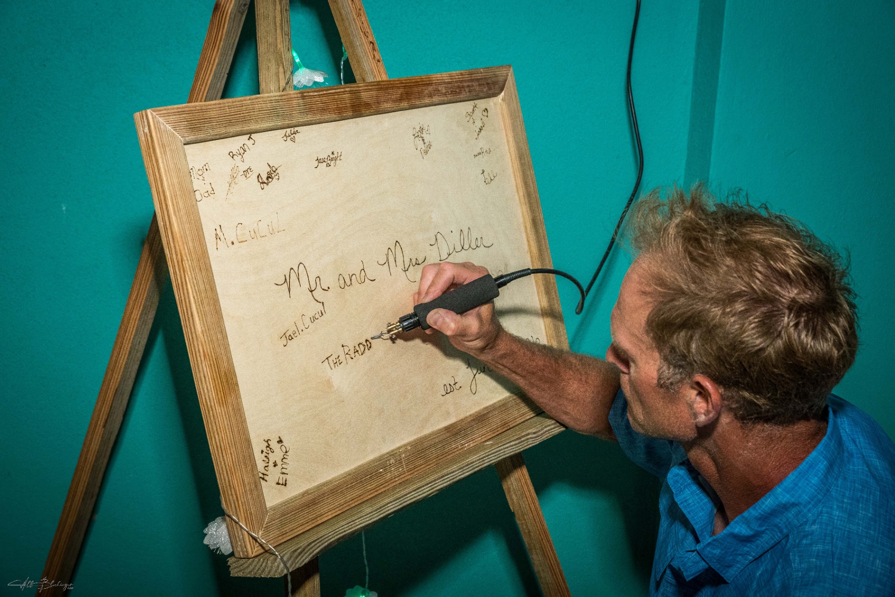 Guest wood-burning a signature into the custom Mr and Mrs Diller wedding guest board