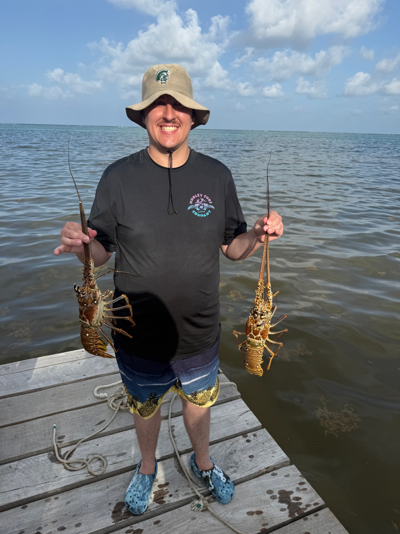 Playa Blanca guest holding fresh Belize spiny lobster on the dock