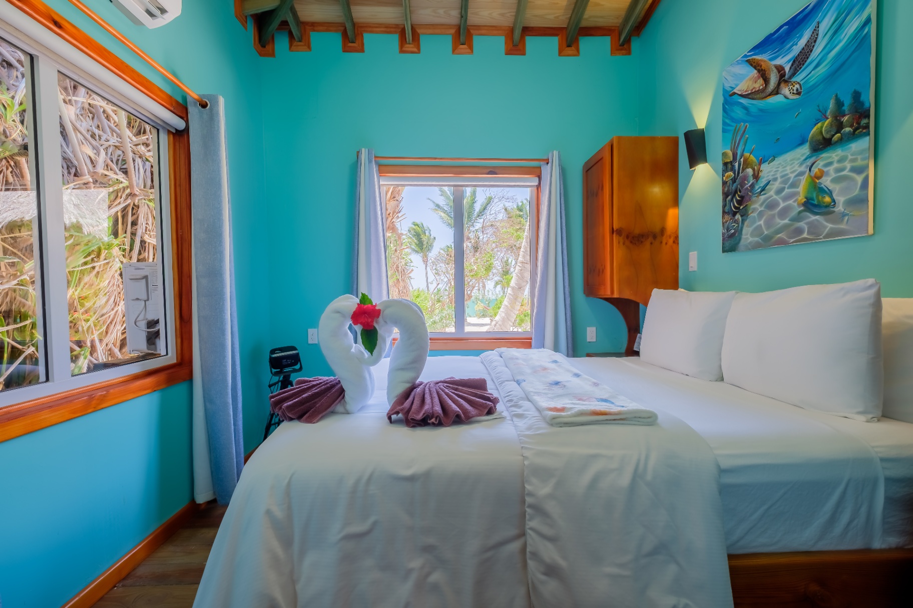 King bedroom with reef artwork and palm-framed sea view