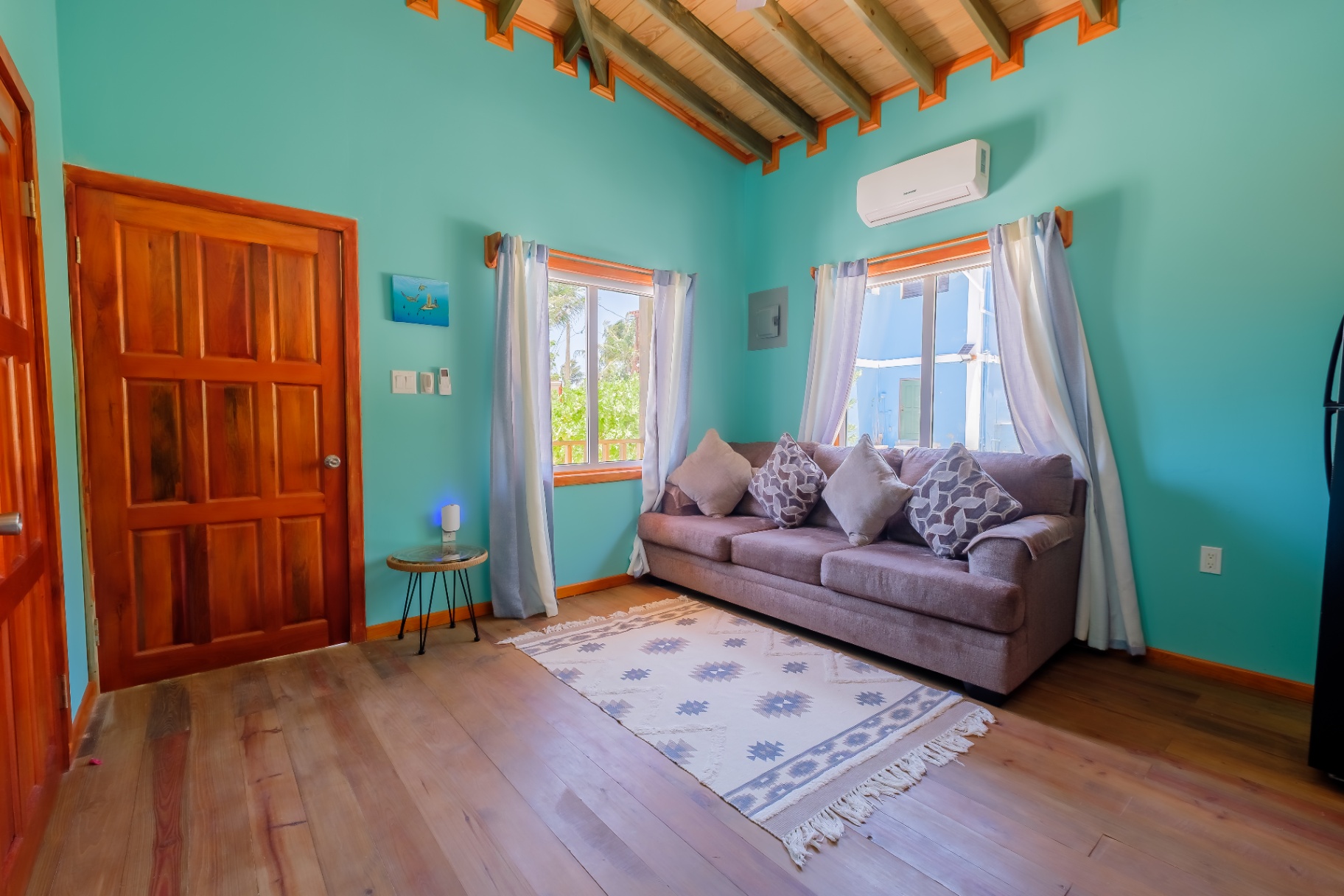 Open living room with hardwood floors, sleeper sofa, and vaulted pine beams