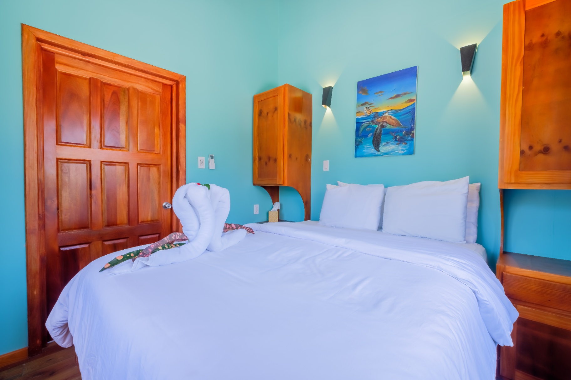 Bedroom with king bed, turquoise walls, and signature sea turtle painting
