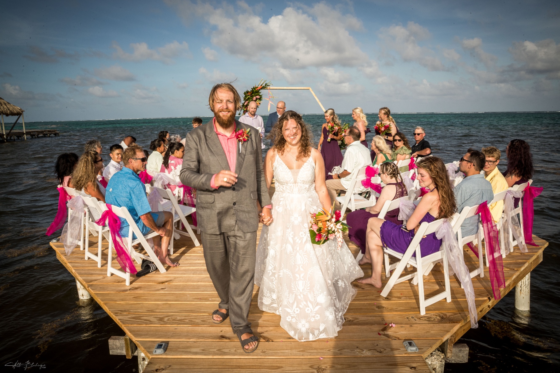 Newly married couple walking down the dock aisle past seated guests after the ceremony