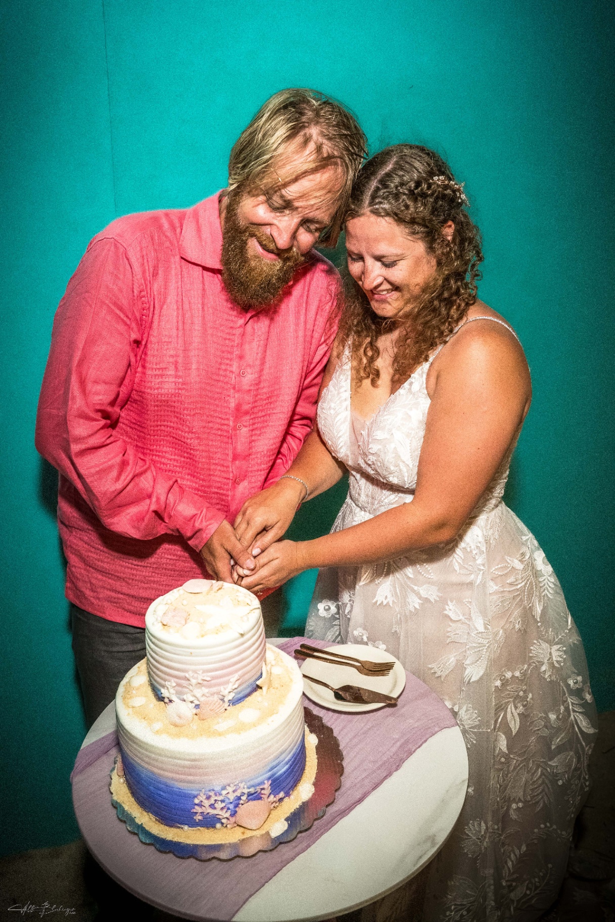 Bride and groom cutting their ombre blue wedding cake decorated with seashells
