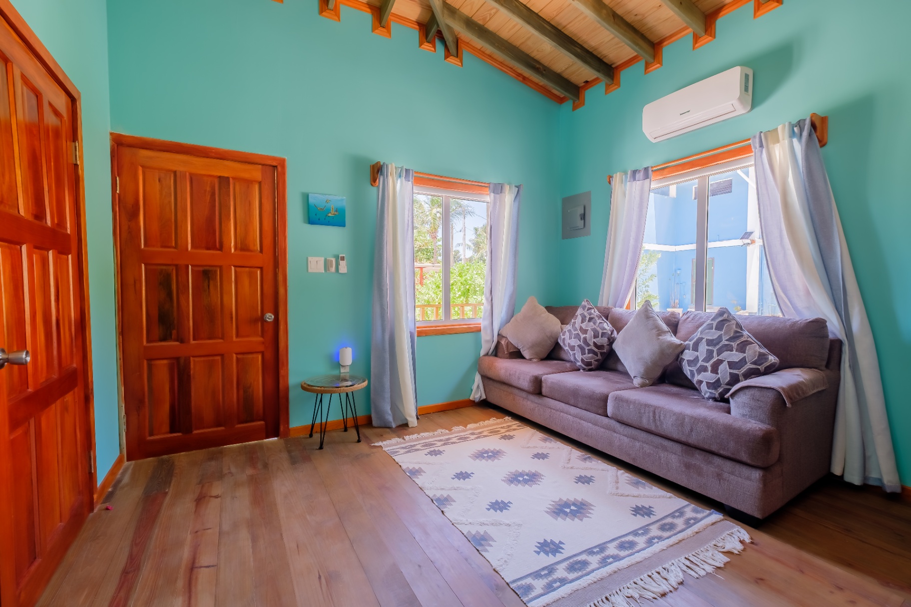 Turquoise living room with sofa, vaulted beam ceiling, and tropical windows