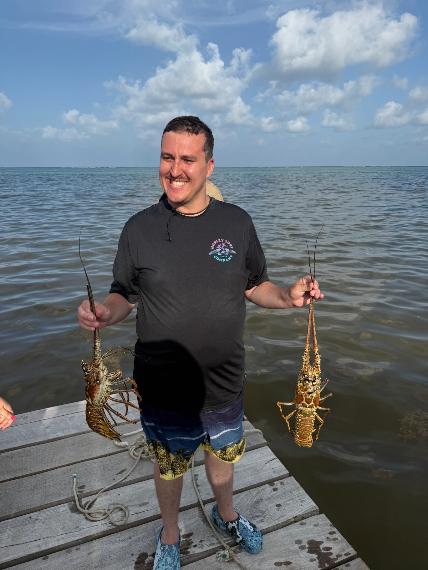 Playa Blanca guest holding fresh Belize spiny lobster on the dock