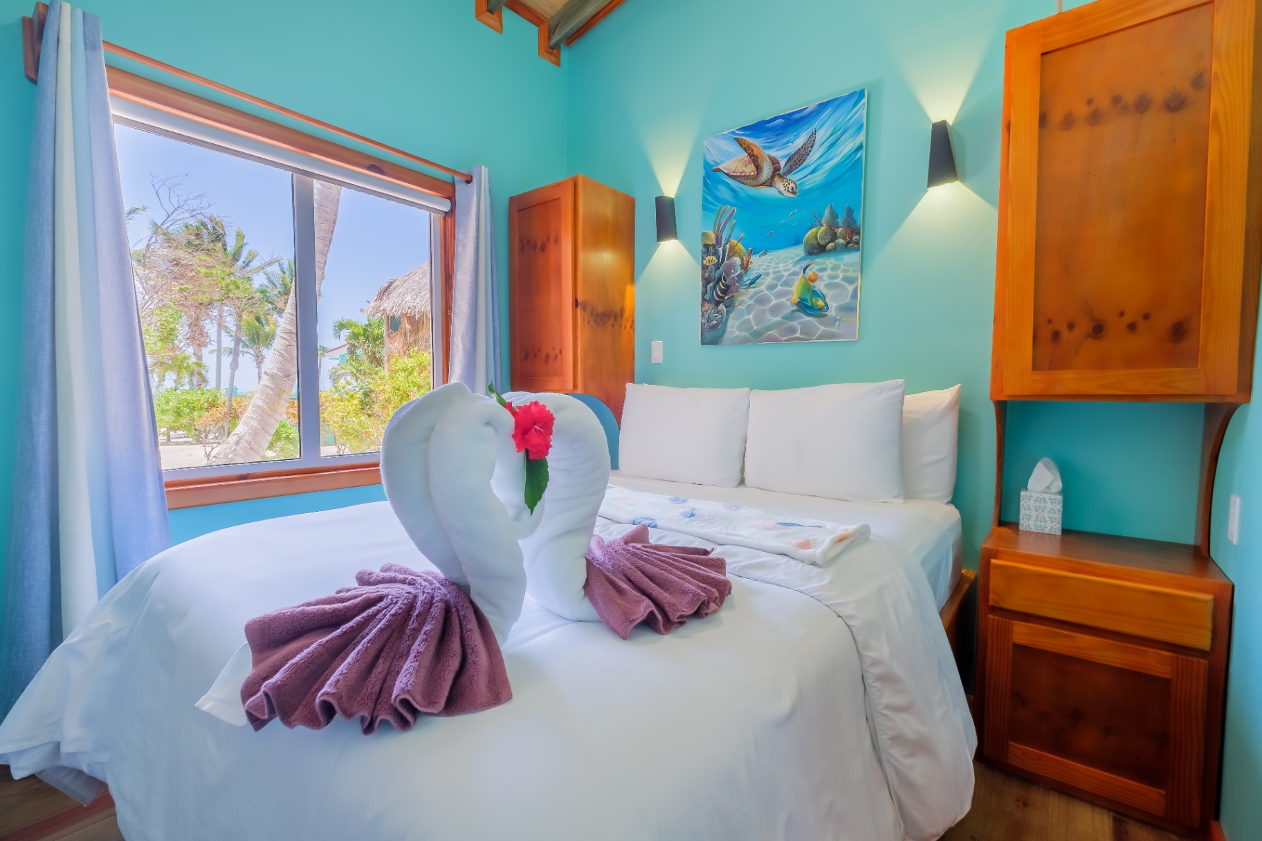 Queen bedroom with sea turtle artwork and palm-framed beach window
