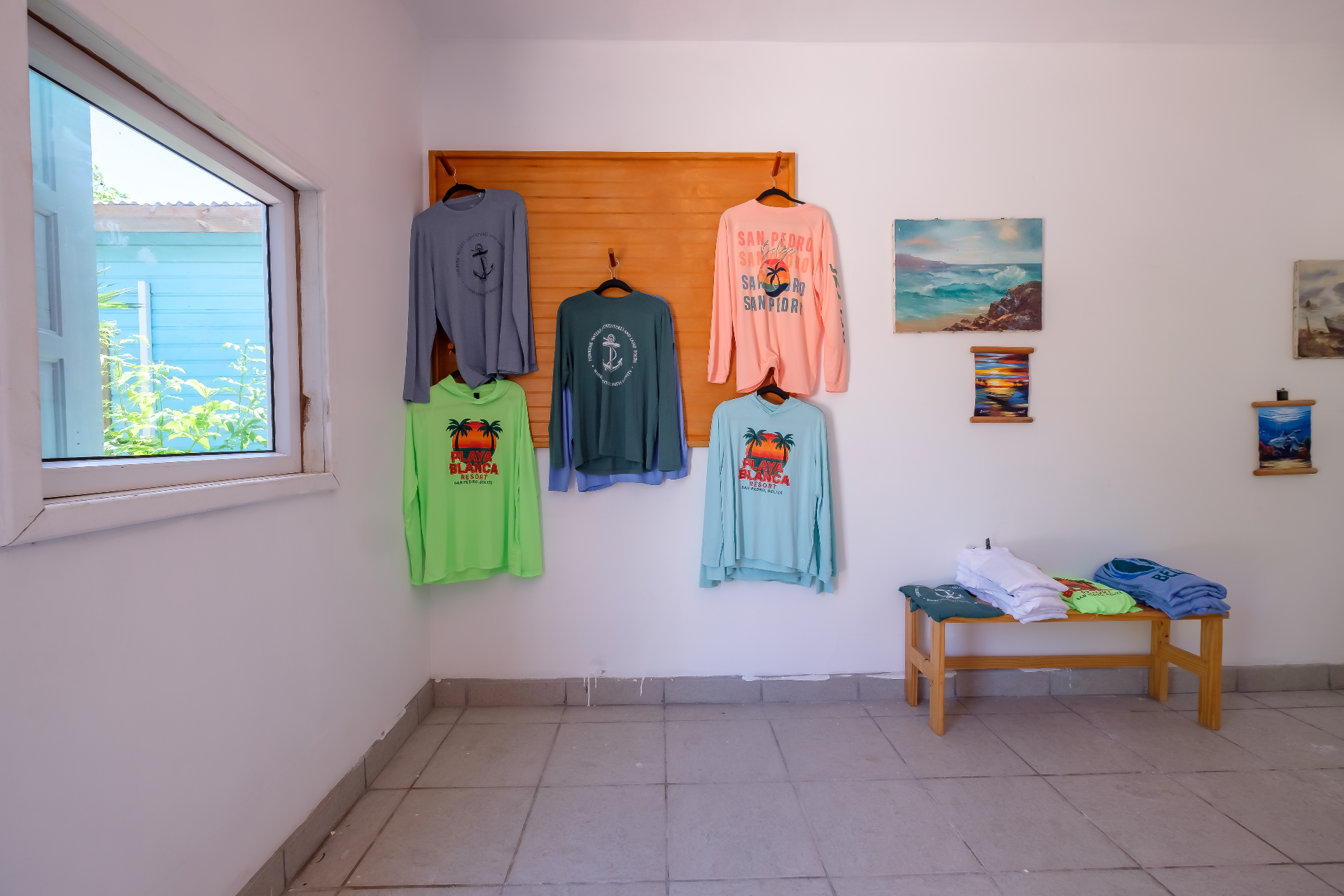 Playa Blanca and San Pedro long-sleeve shirts displayed on a wooden wall rack