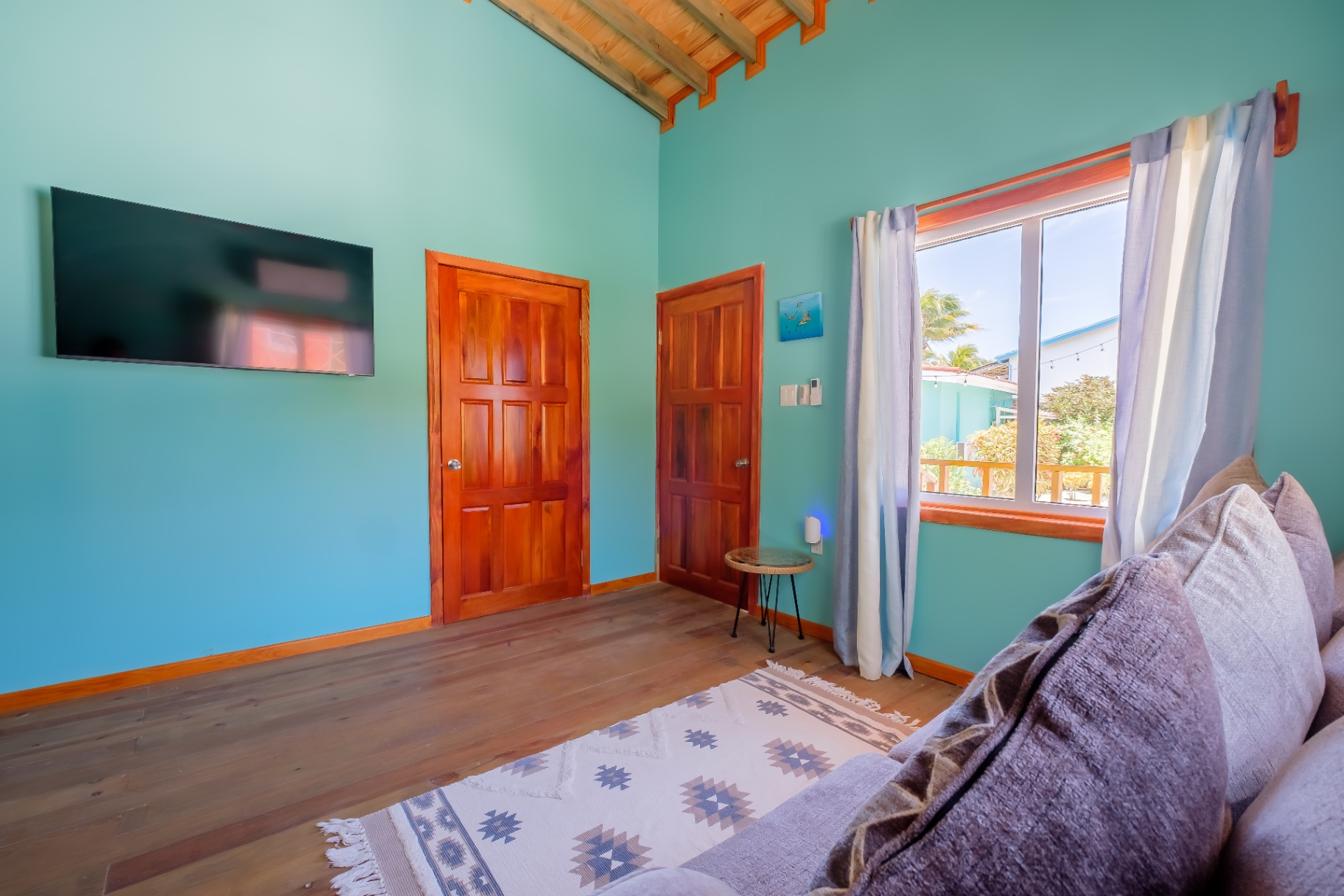 Living room with wall-mounted TV, doors to bedrooms, and garden view window