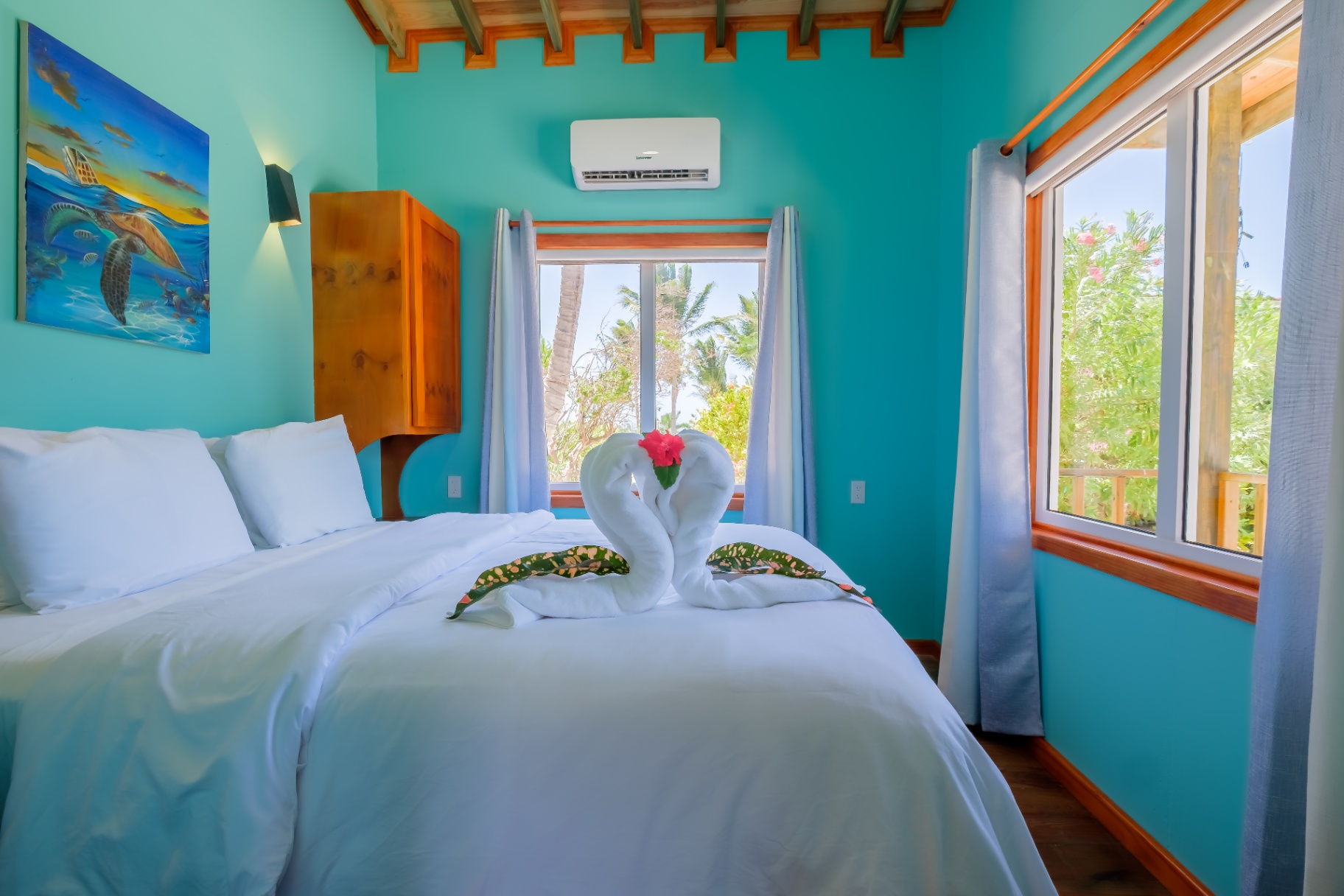 Queen bedroom with towel swans, turtle art, and garden views