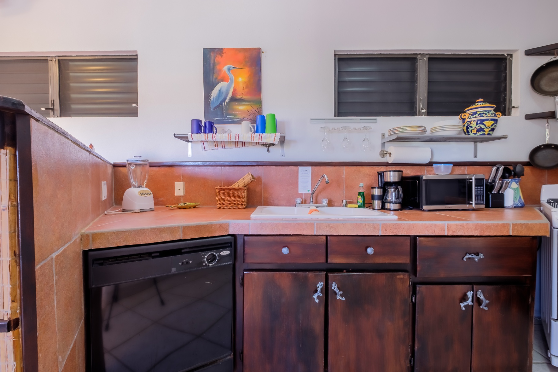 Kitchen with heron painting, dishwasher, and terracotta tile