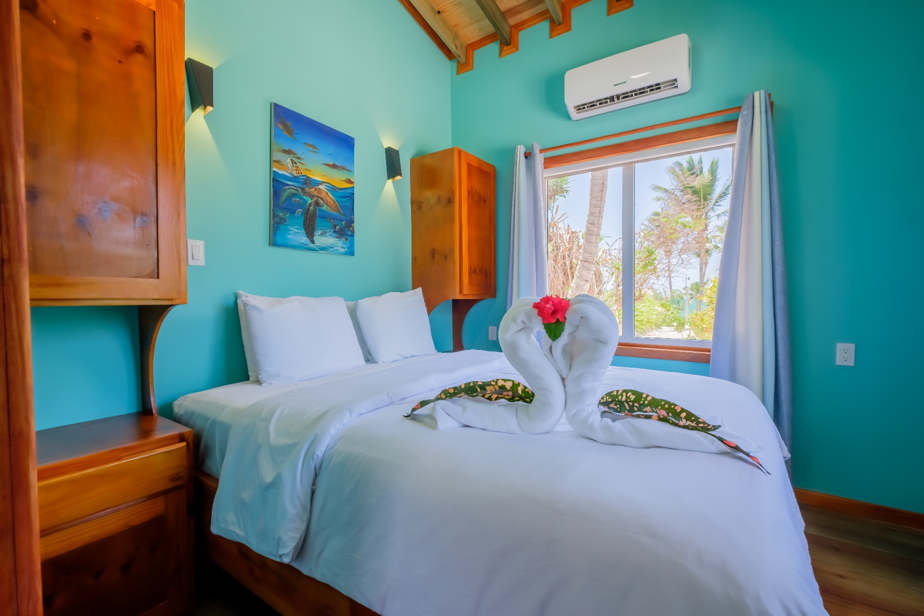 Queen bedroom with turtle painting and palm-framed sea view