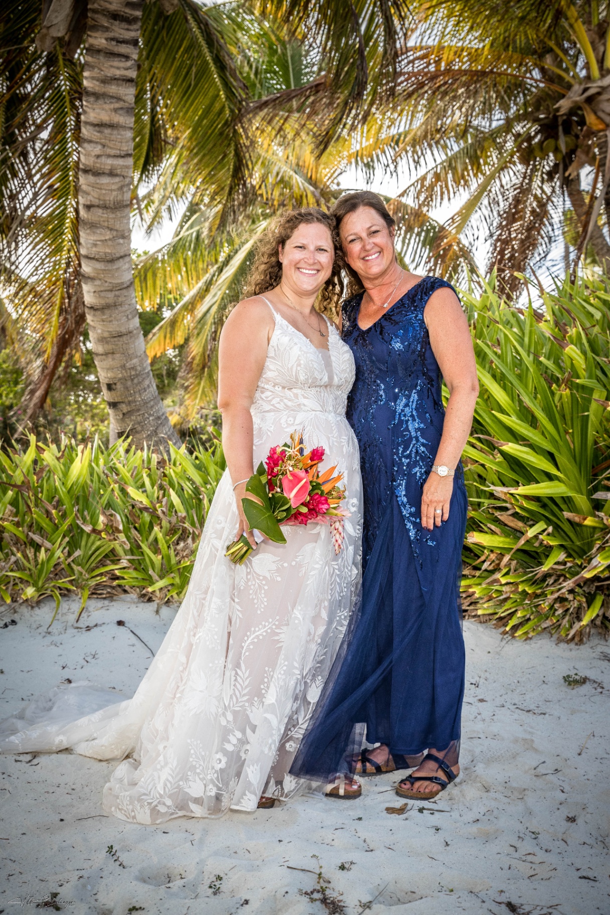 Bride and her mother under the palms with a tropical bouquet on the Playa Blanca beach