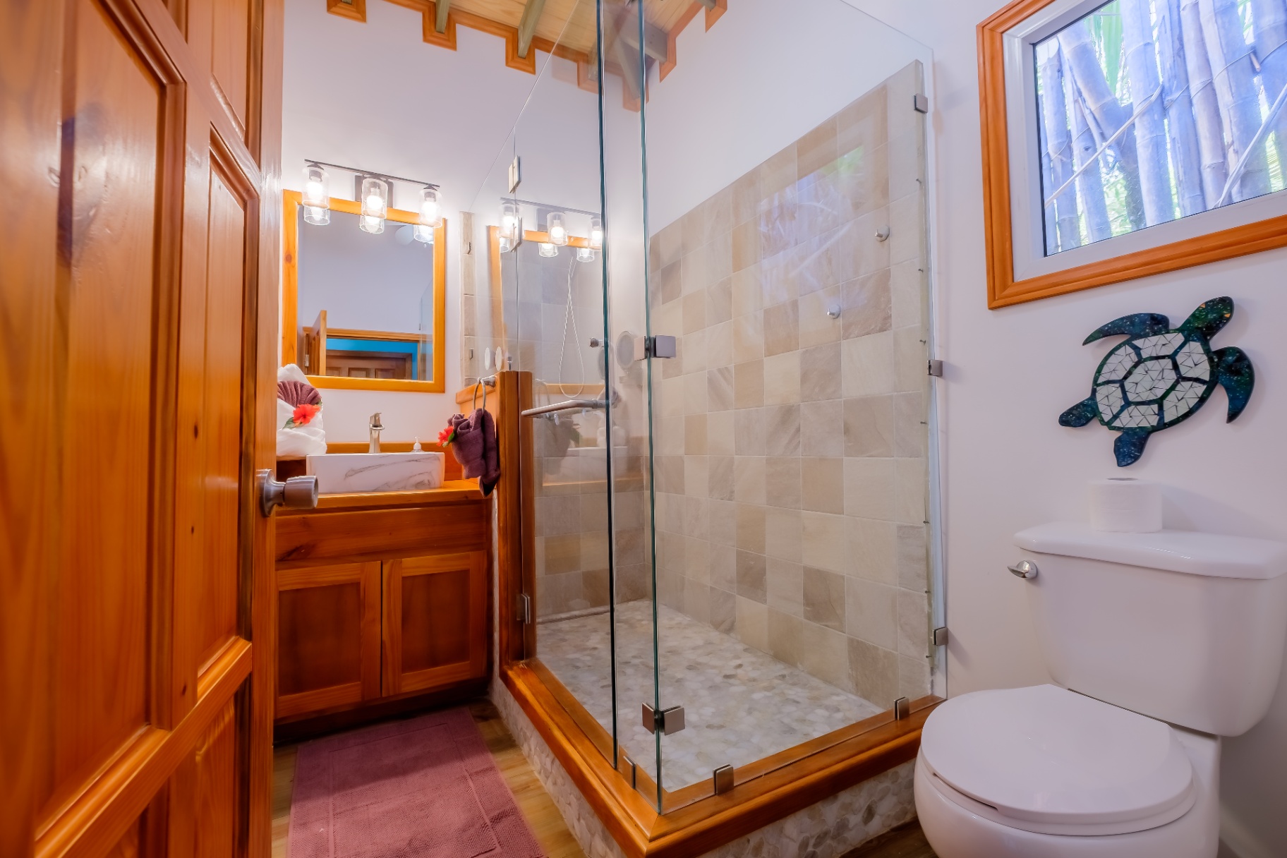 Bathroom with glass walk-in shower, hardwood vanity, and turtle mosaic art