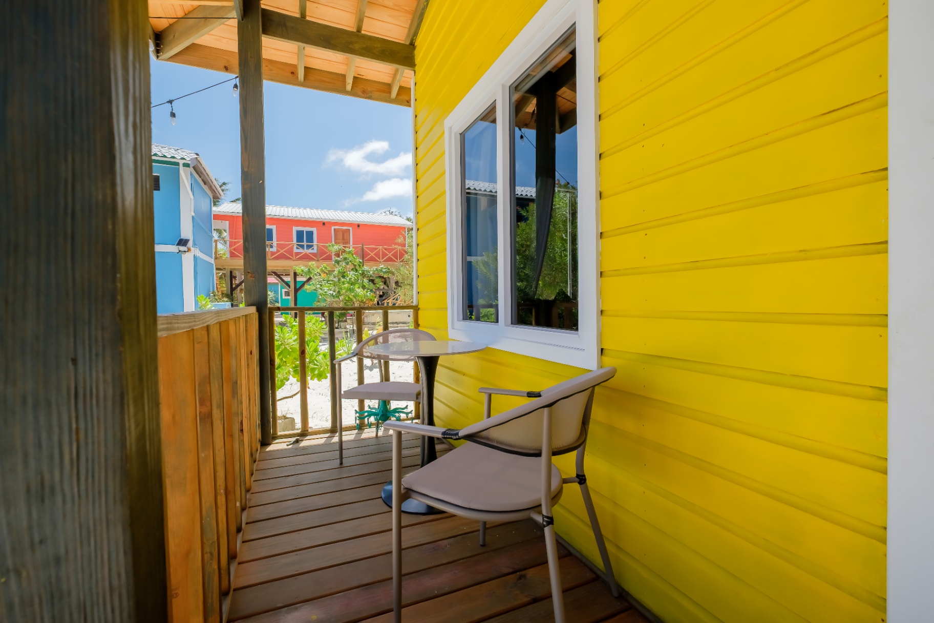 Porch bistro table and chair beside bright yellow siding