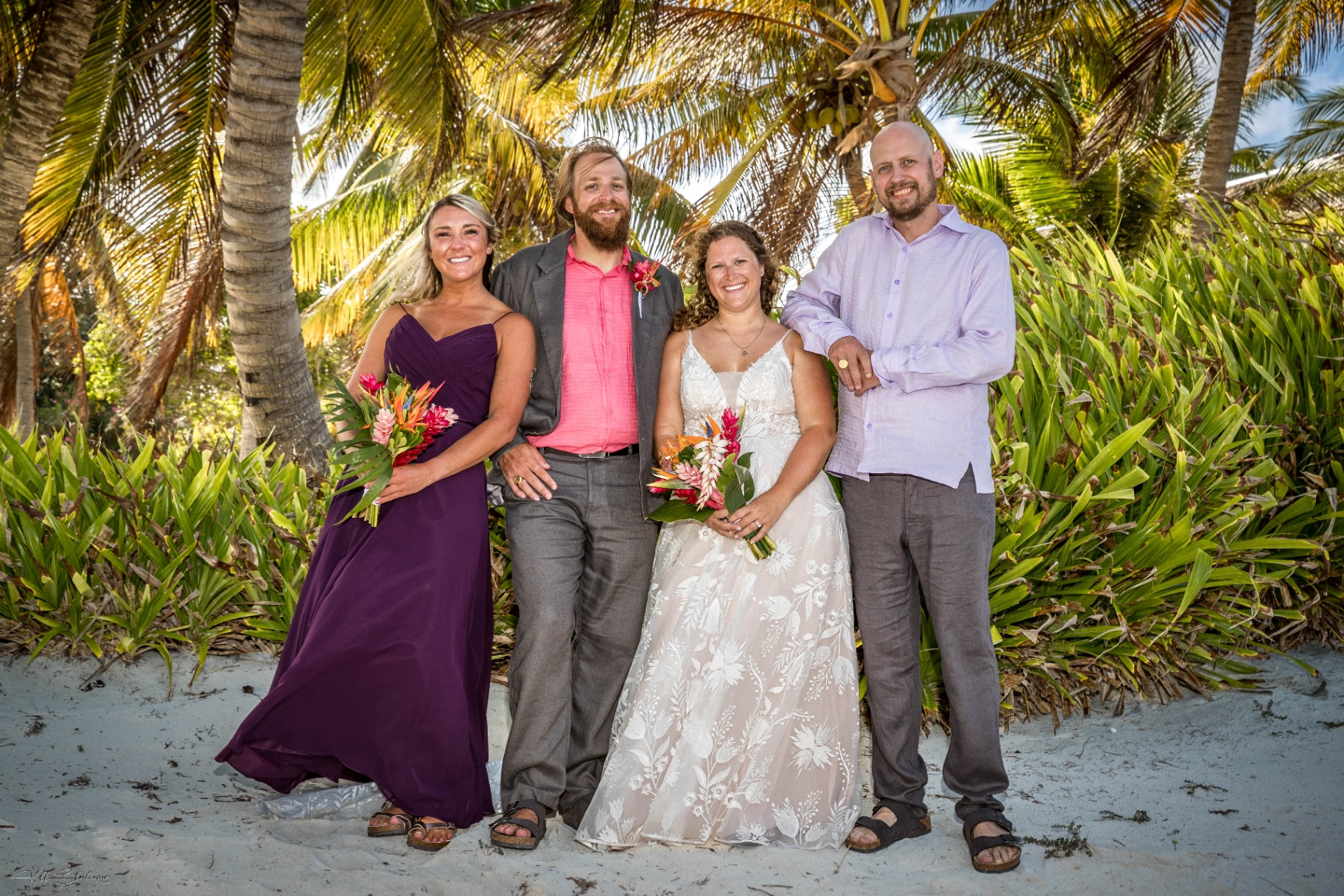 Bride and groom flanked by their siblings for a family portrait on the beach