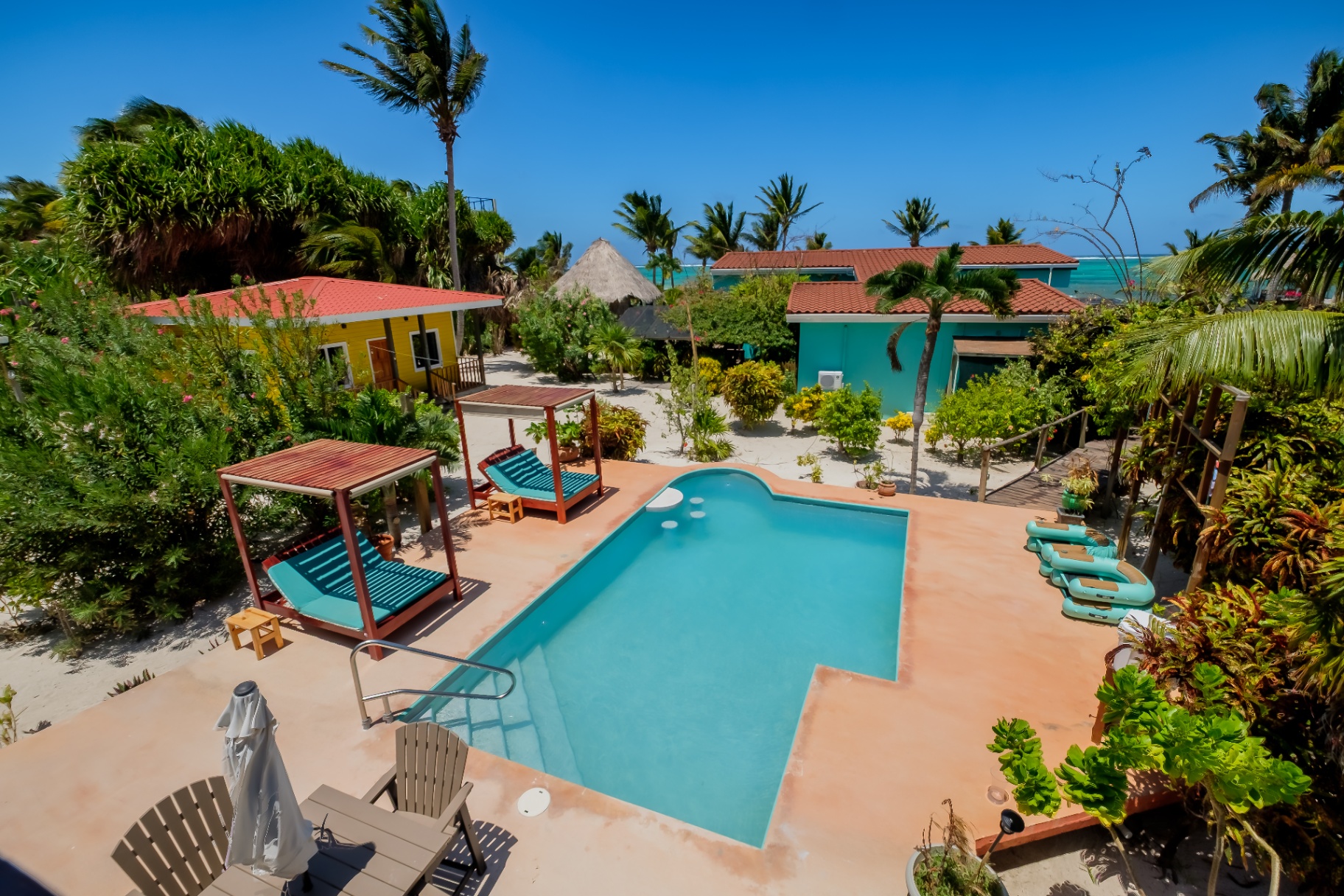 Pool, cabana daybeds, and palms framing the Caribbean